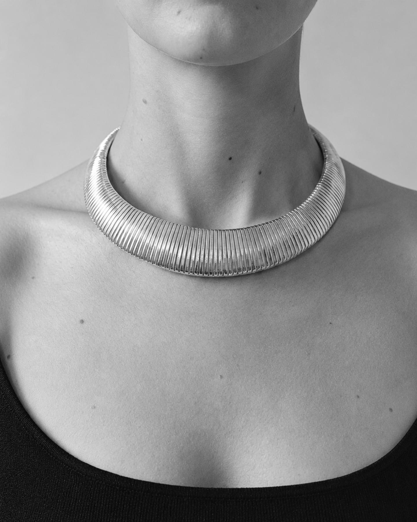Silver necklace on a person against a neutral background