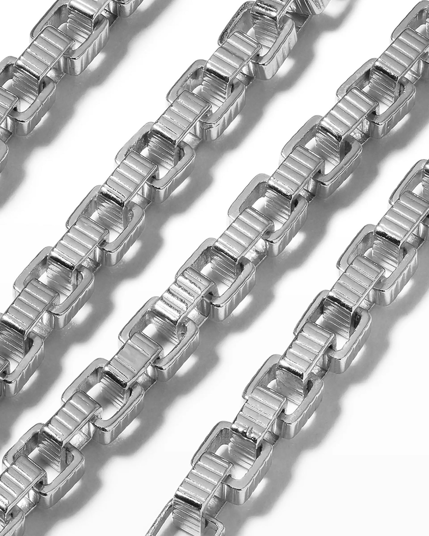 A close up of a rhodium-plated chain princess necklace with a square clasp, laid out on a white background.