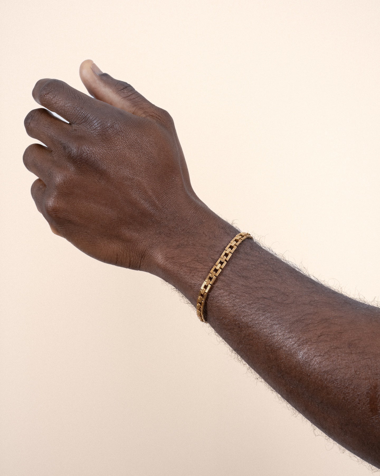 A gold-plated Aurelia Chain bracelet with interlocking square links worn by a model.