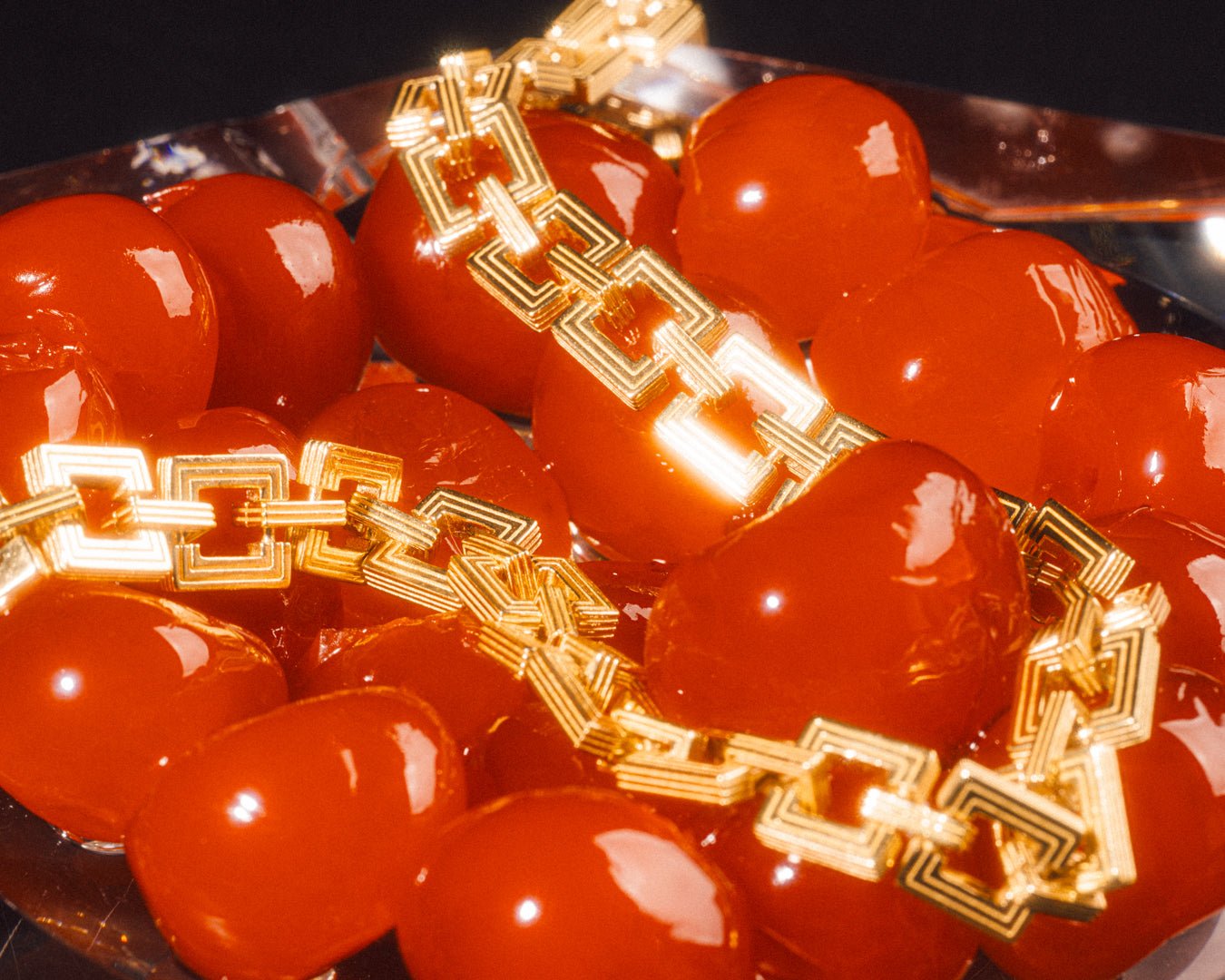 Gold geometric link bracelet styled among red cherries