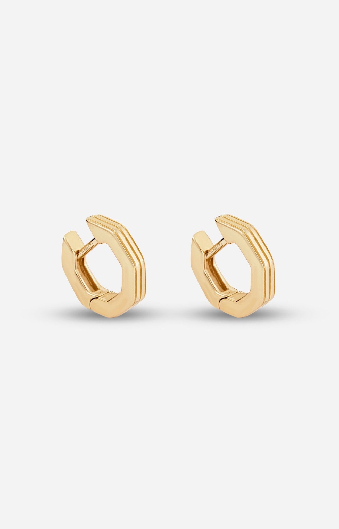 A pair of gold-plated octagon-shaped huggies earrings with linear engravings, displayed against a white background.