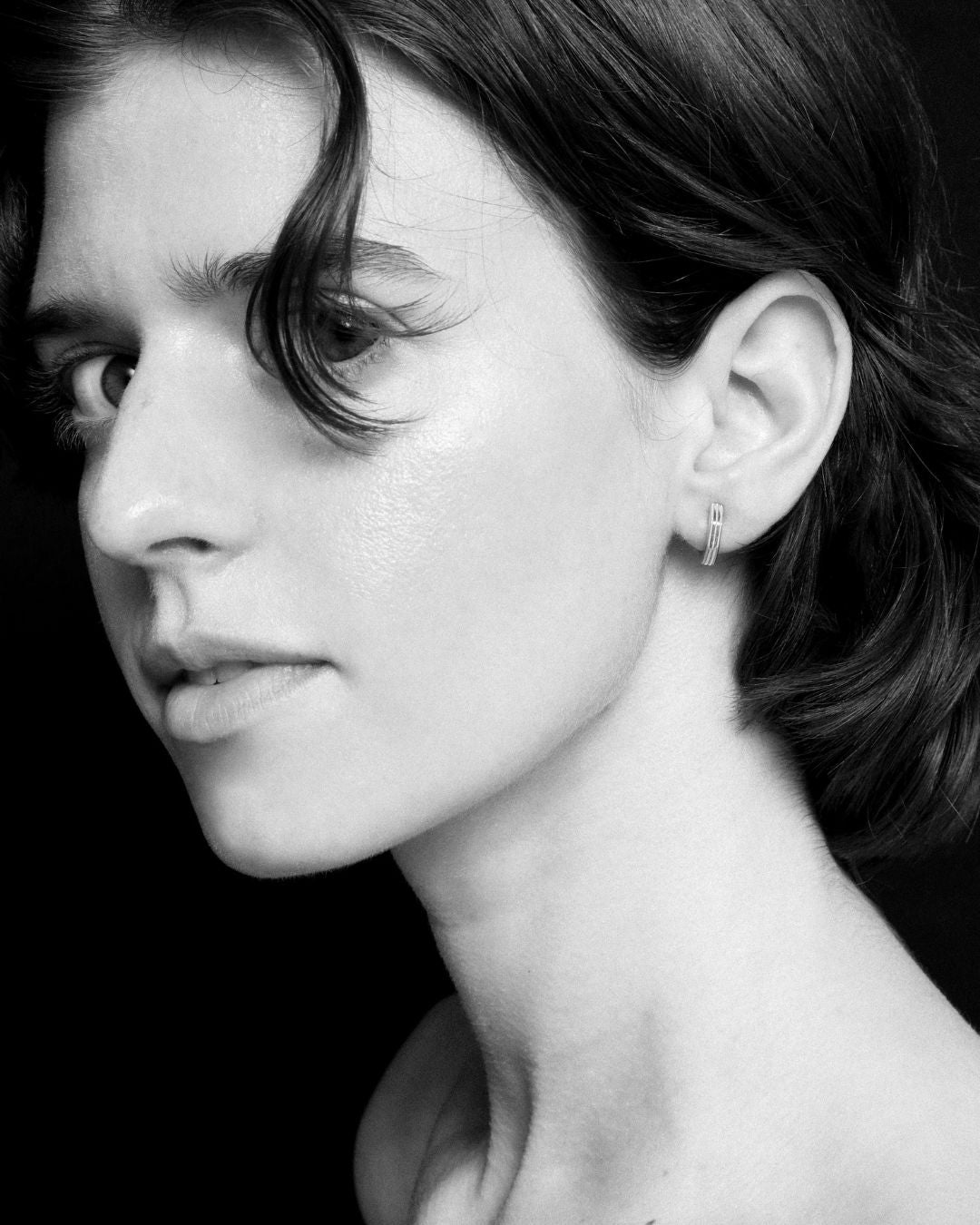 Black and white close-up of a woman's face with huggies earrings.