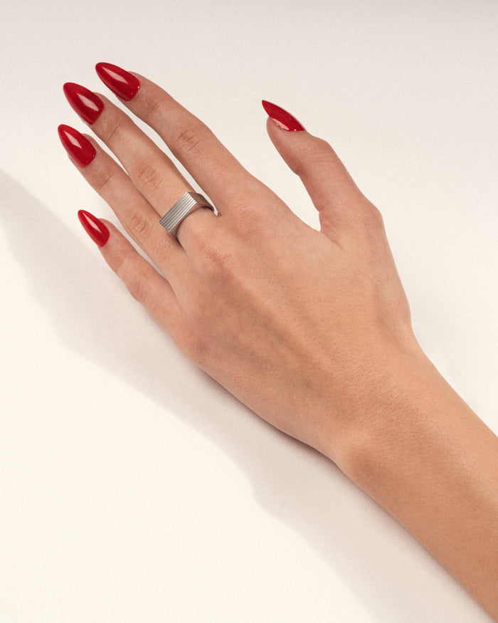 Silver ridged geometric ring worn on hand.