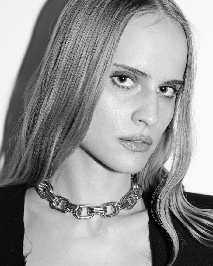 Black and white portrait of a person wearing a chain necklace.
