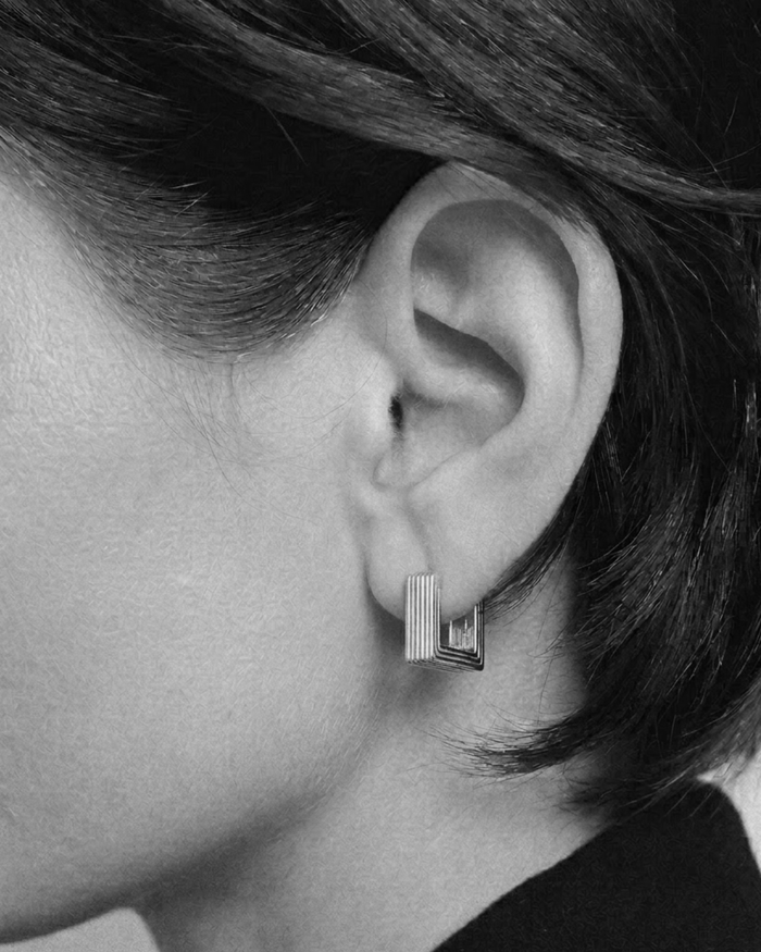 Close-up of an ear wearing a geometric earring with a blurred background