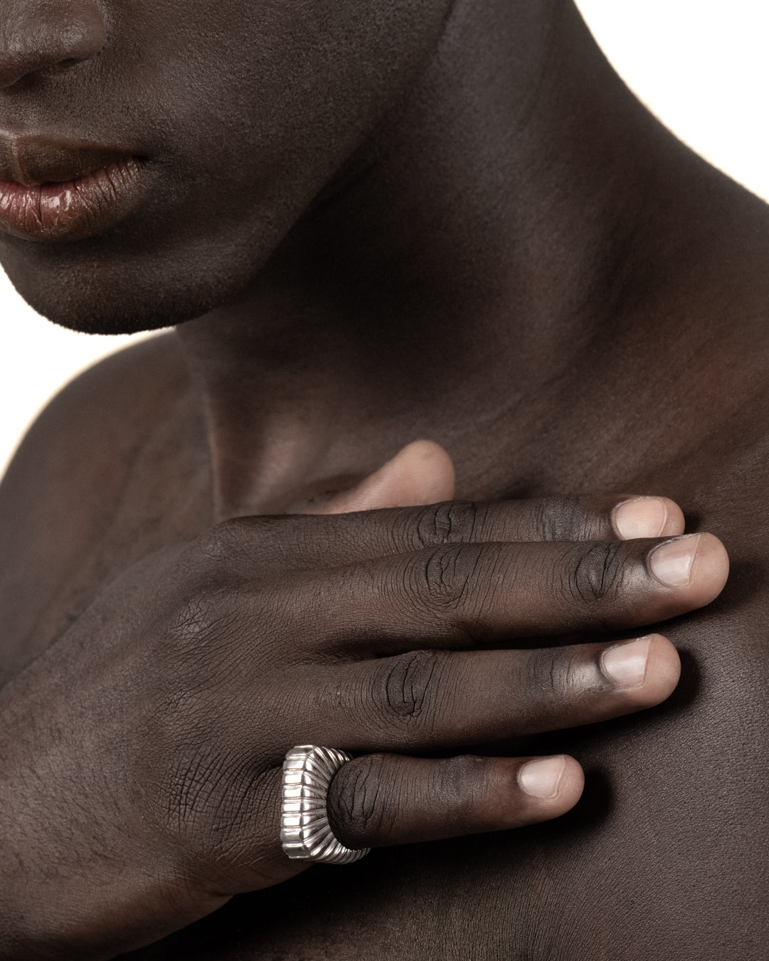 Bold silver ridged statement ring worn on a hand, shown in a lifestyle close-up.