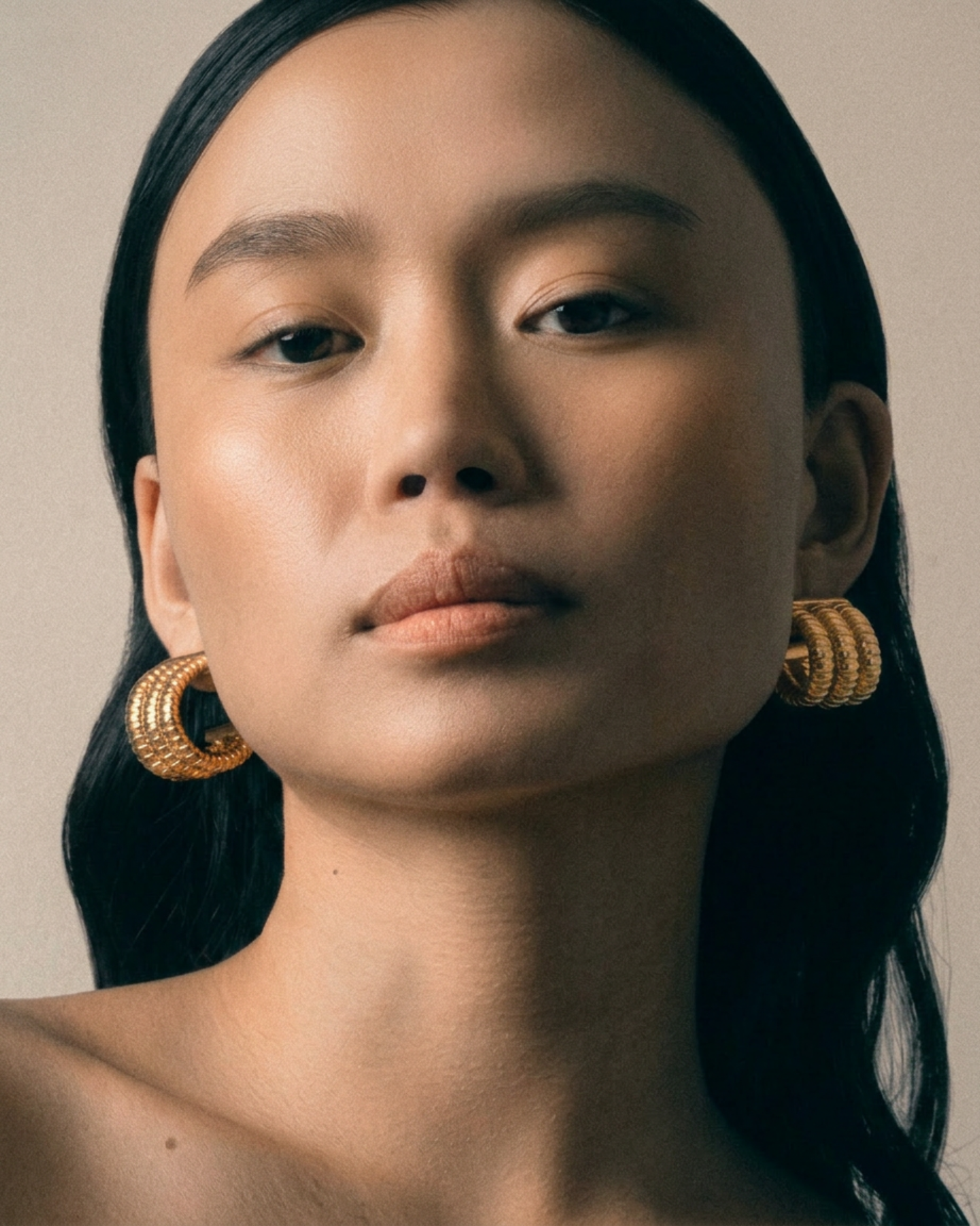 Woman wearing gold hoop earrings against a neutral background