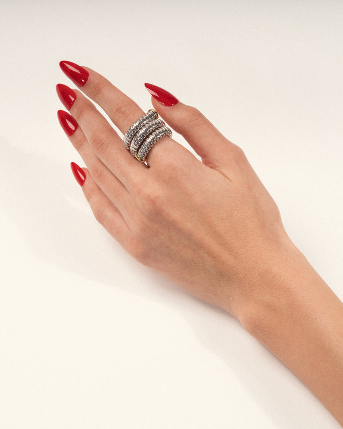 Stacked silver coil statement ring worn on a hand with red nails, shown in a lifestyle close-up.