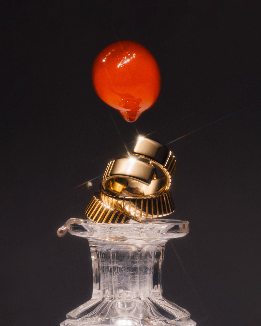 A gold-plated, twist-style ring placed on a glass. 
