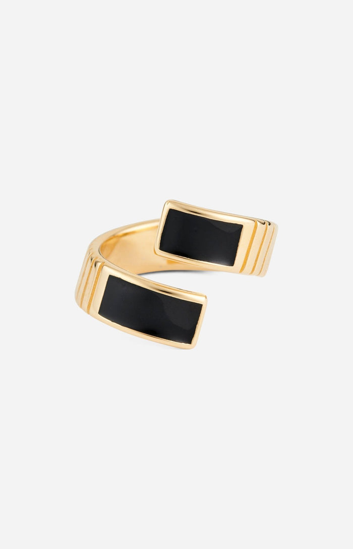 A gold-plated twist ring with polished black enamel stripes at the tips, with a textured surface and signature linear engravings.
