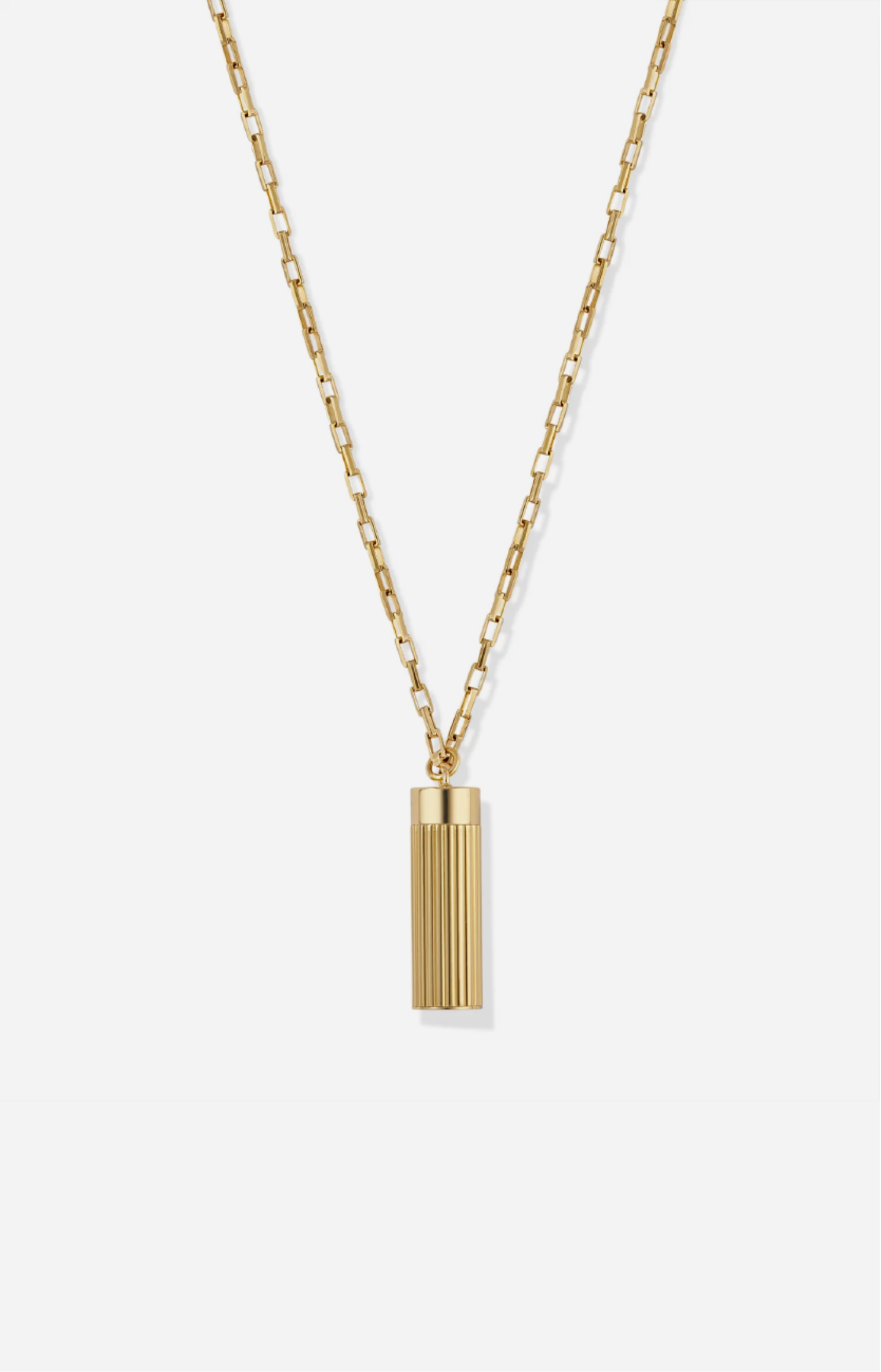 Gold necklace with a cylindrical pendant on a white background
