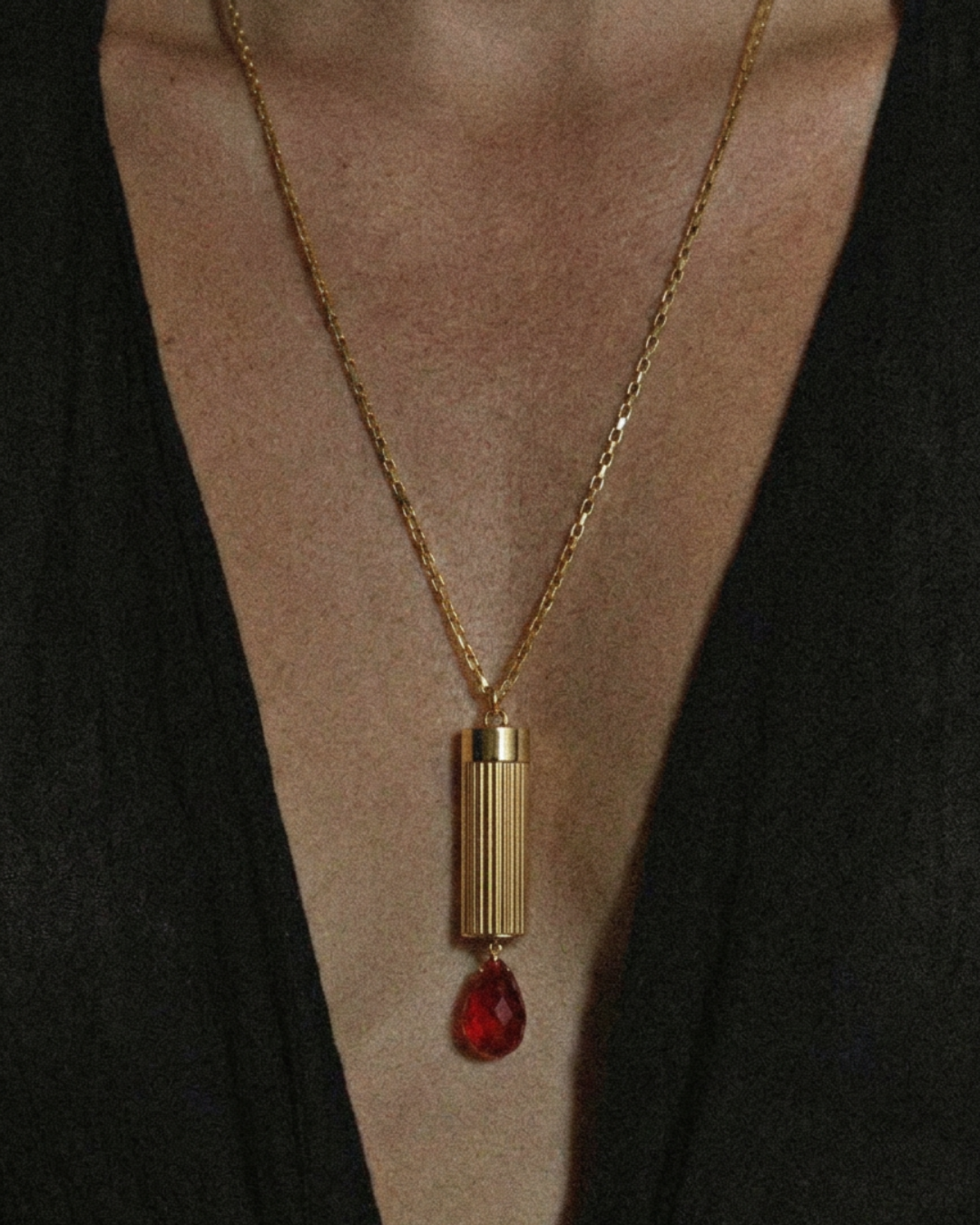 Gold necklace with a red pendant on a model