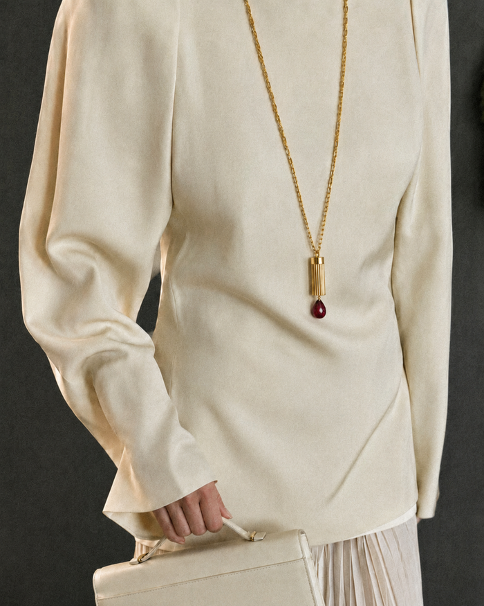 Gold necklace with a red pendant on a white background