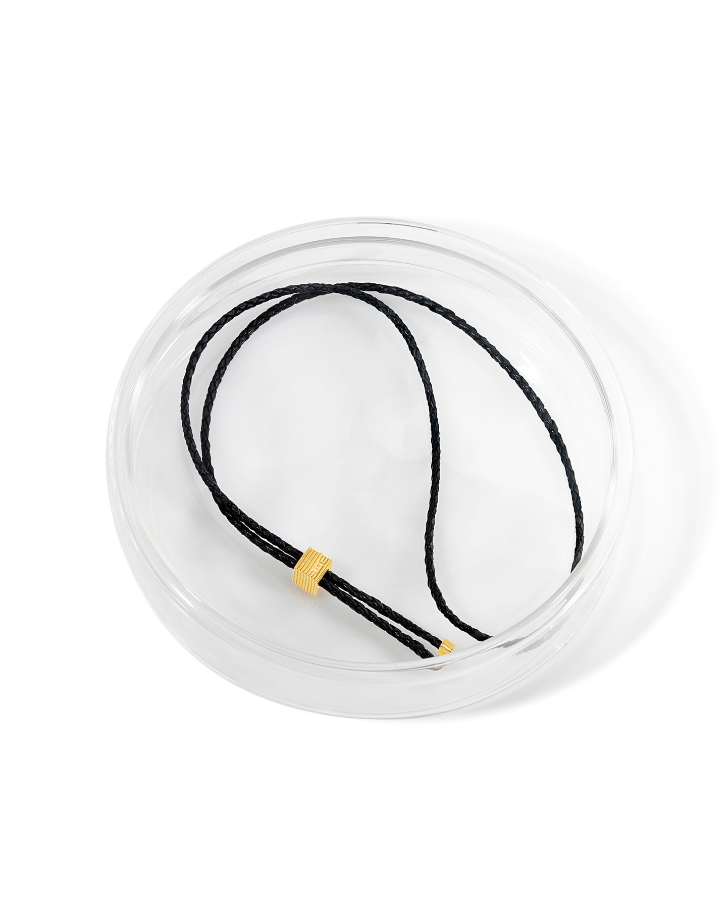 Black adjustable bolo tie necklace with gold slider detail and metal end caps in a glass case.  