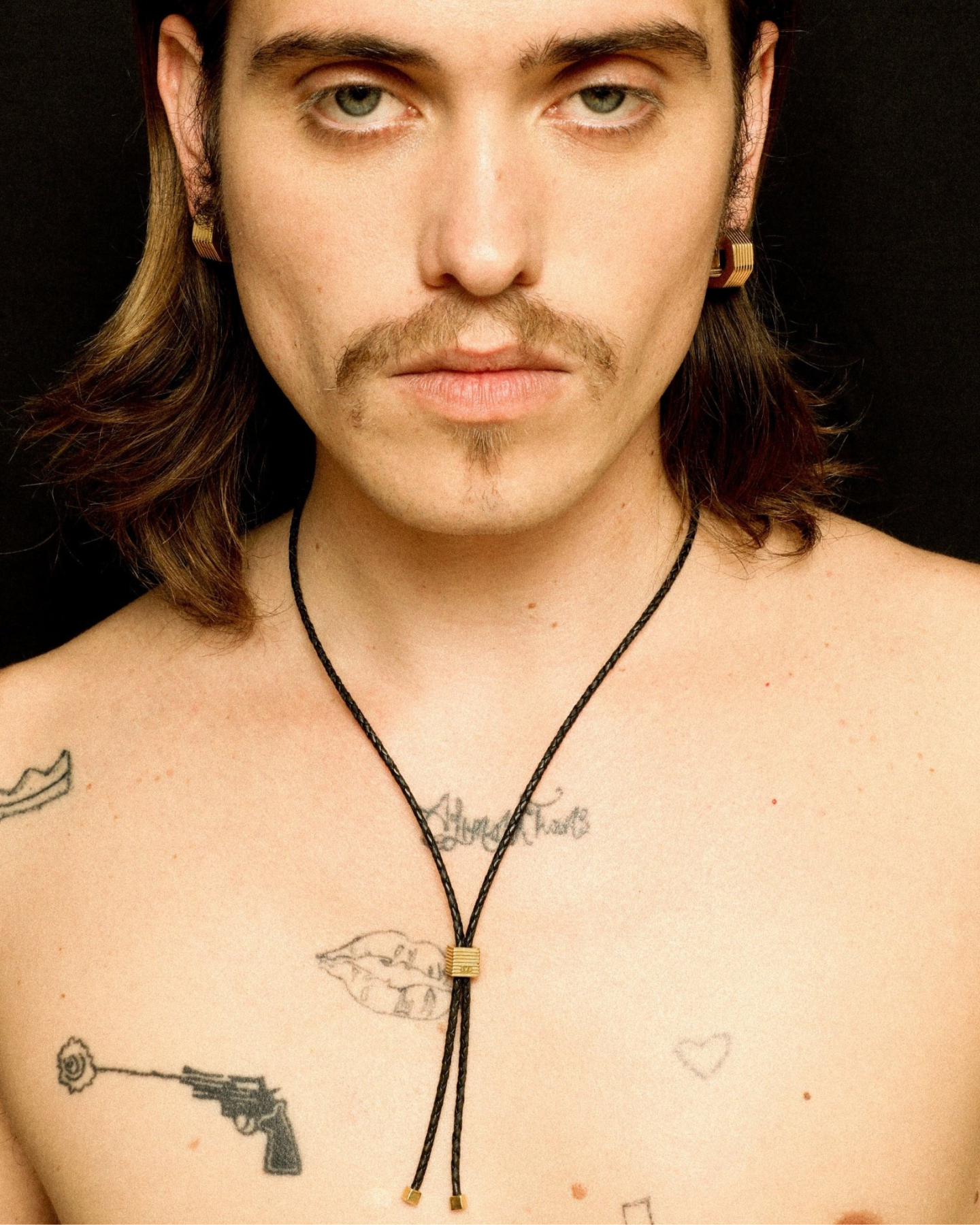 Black adjustable bolo tie necklace with gold slider detail and metal end caps worn by a model.