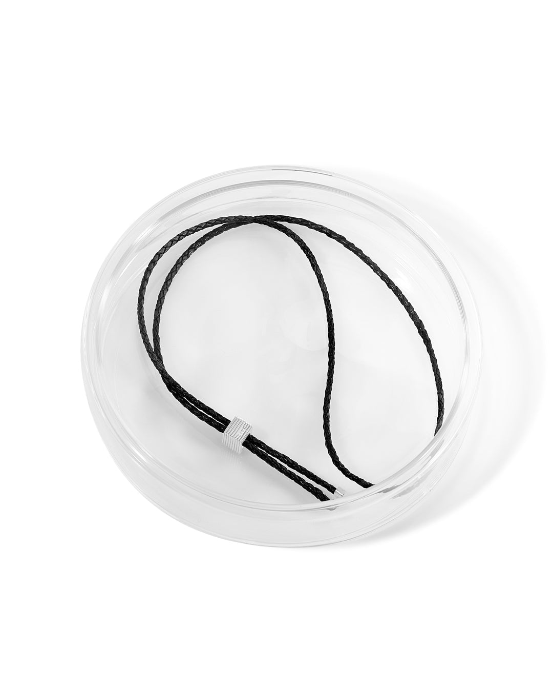 A bolo tie with an adjustable silhouette crafted from braided leather, with signature rhodium-plated cubes at the fastening and tips in a glass case. 