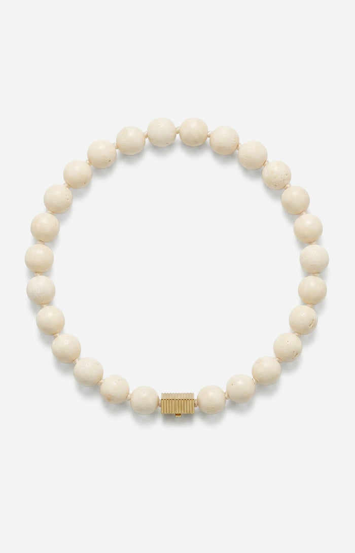 White beaded bracelet with a gold clasp on a white background