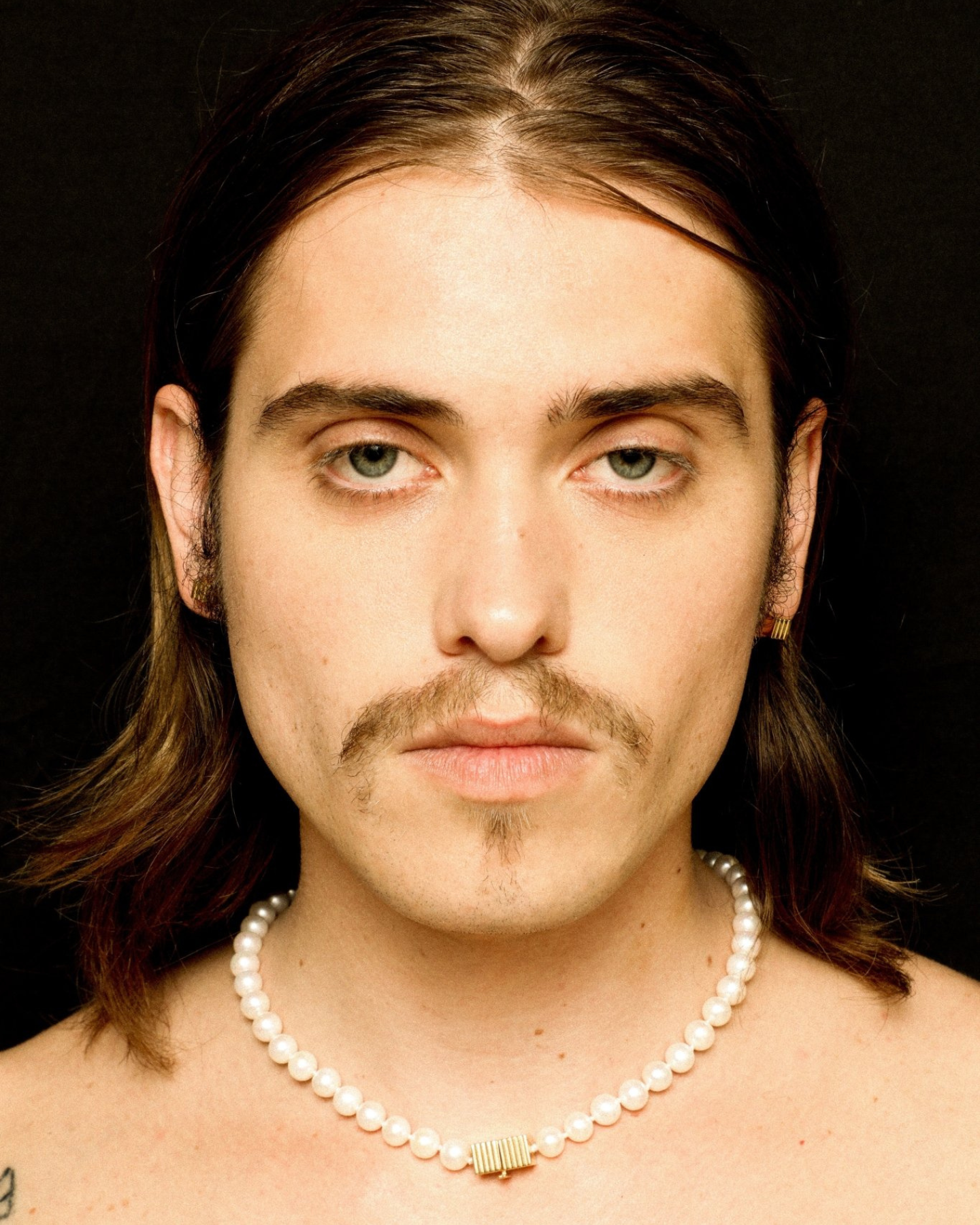 Pearl necklace with a gold clasp worn by a model. 