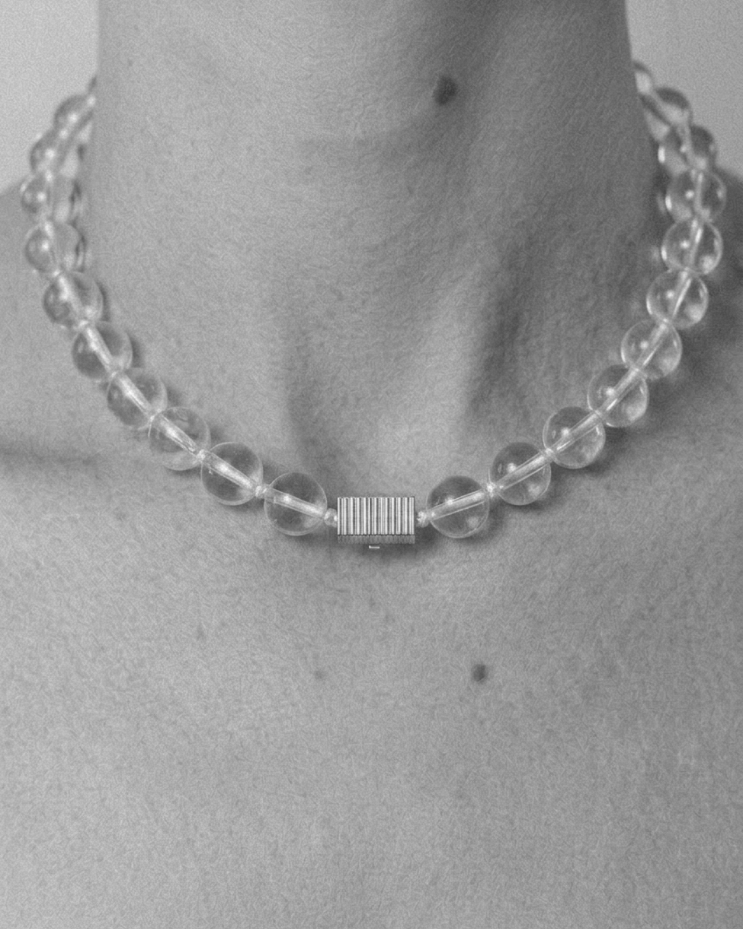 Clear beaded necklace worn by a person on a plain background