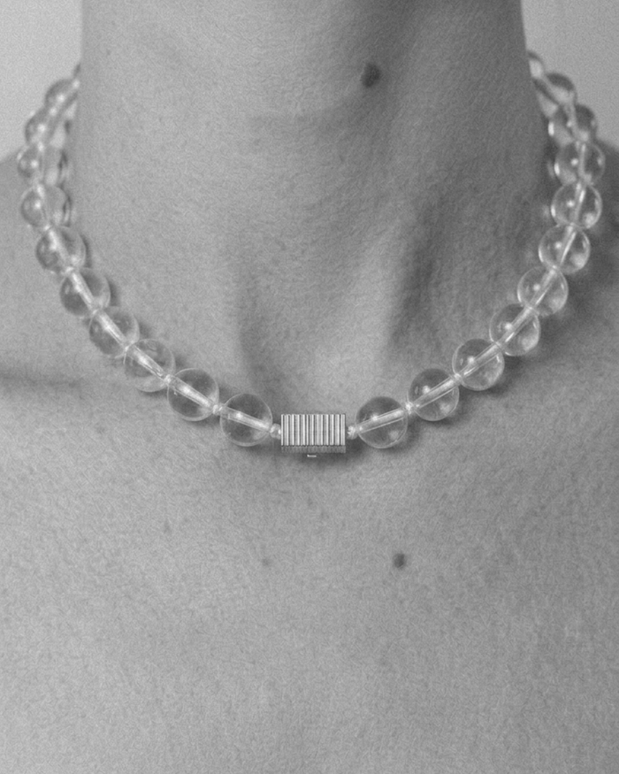 Clear beaded necklace worn by a person on a plain background