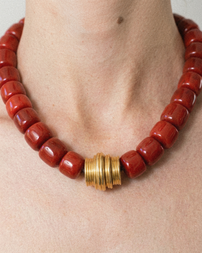 Red coral beaded necklace with a gold clasp on a person's neck