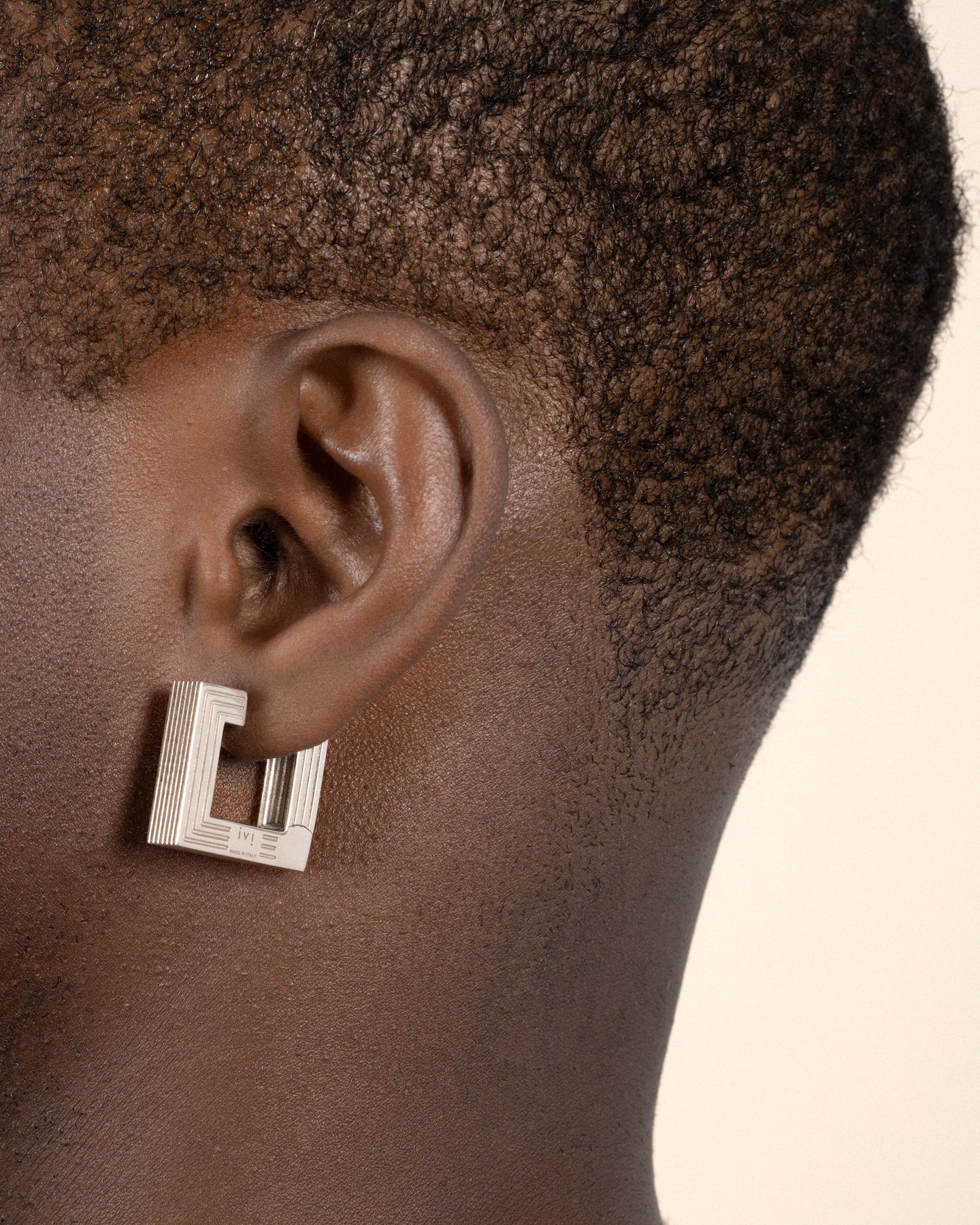 Pair of rhodium-plated medium Aurelia sculptural square hoop earrings worn by a model. 