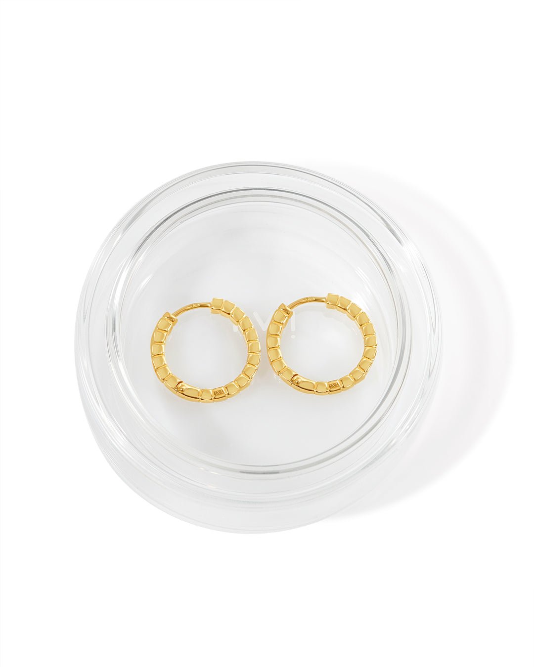 A pair of medium gold-plated Signore hoop earrings with a textured design, resembling a curving row of square beads placed in glass packaging. 