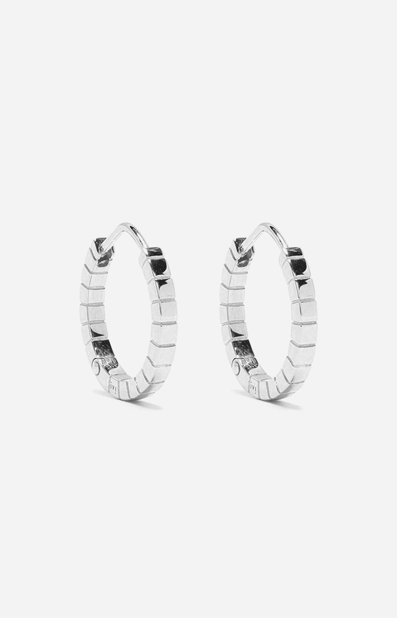 A pair of medium rhodium-plated Signore hoop earrings with a textured design, resembling a curving row of square beads.
