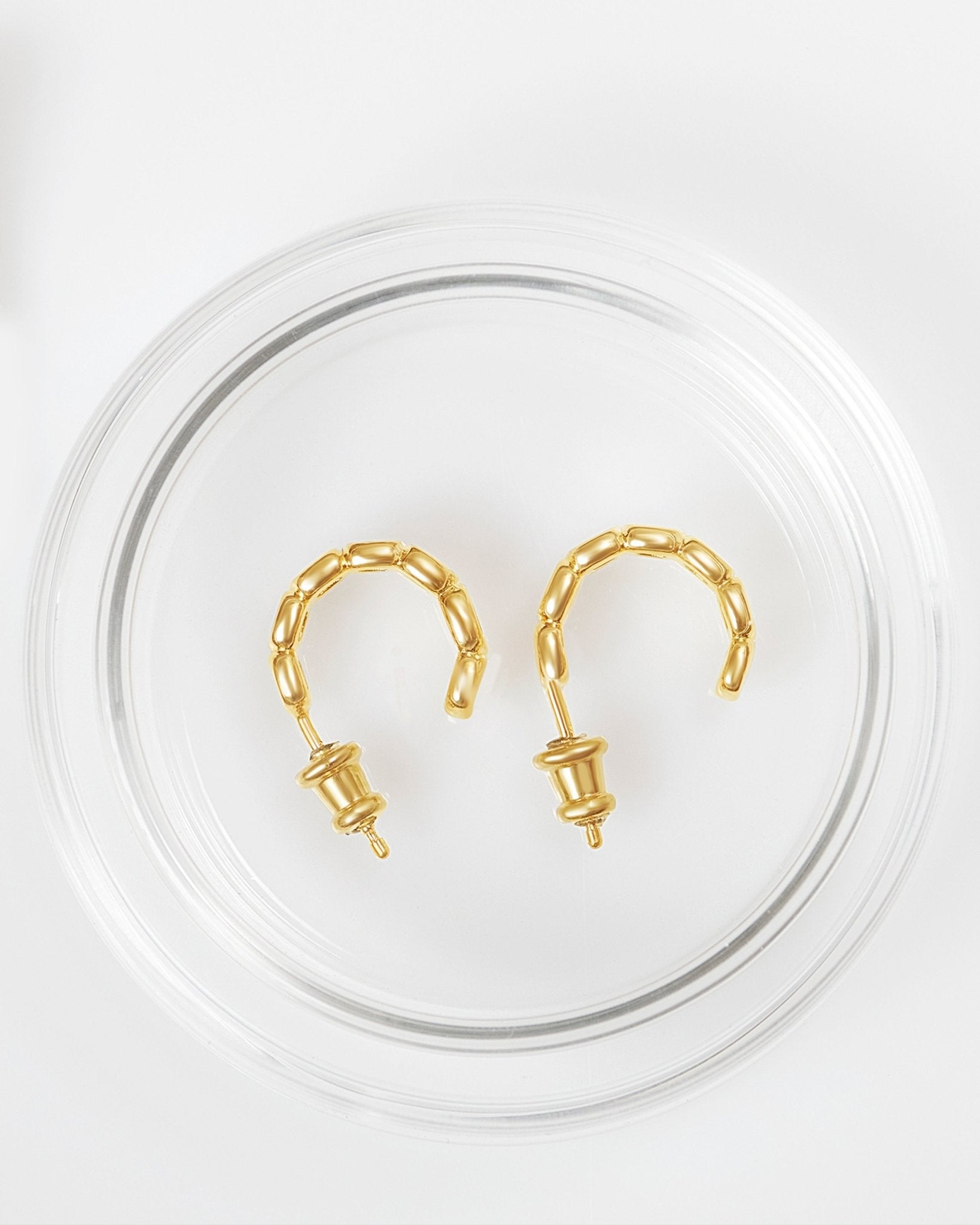 A pair of gold-plated mini toy hoop earrings with oval links in glass packaging. 