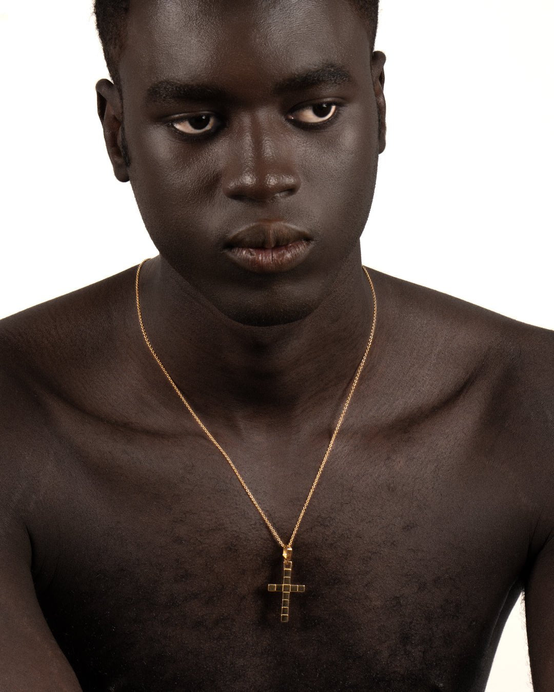 A gold-plated cross necklace with a custom chain worn by a model. 