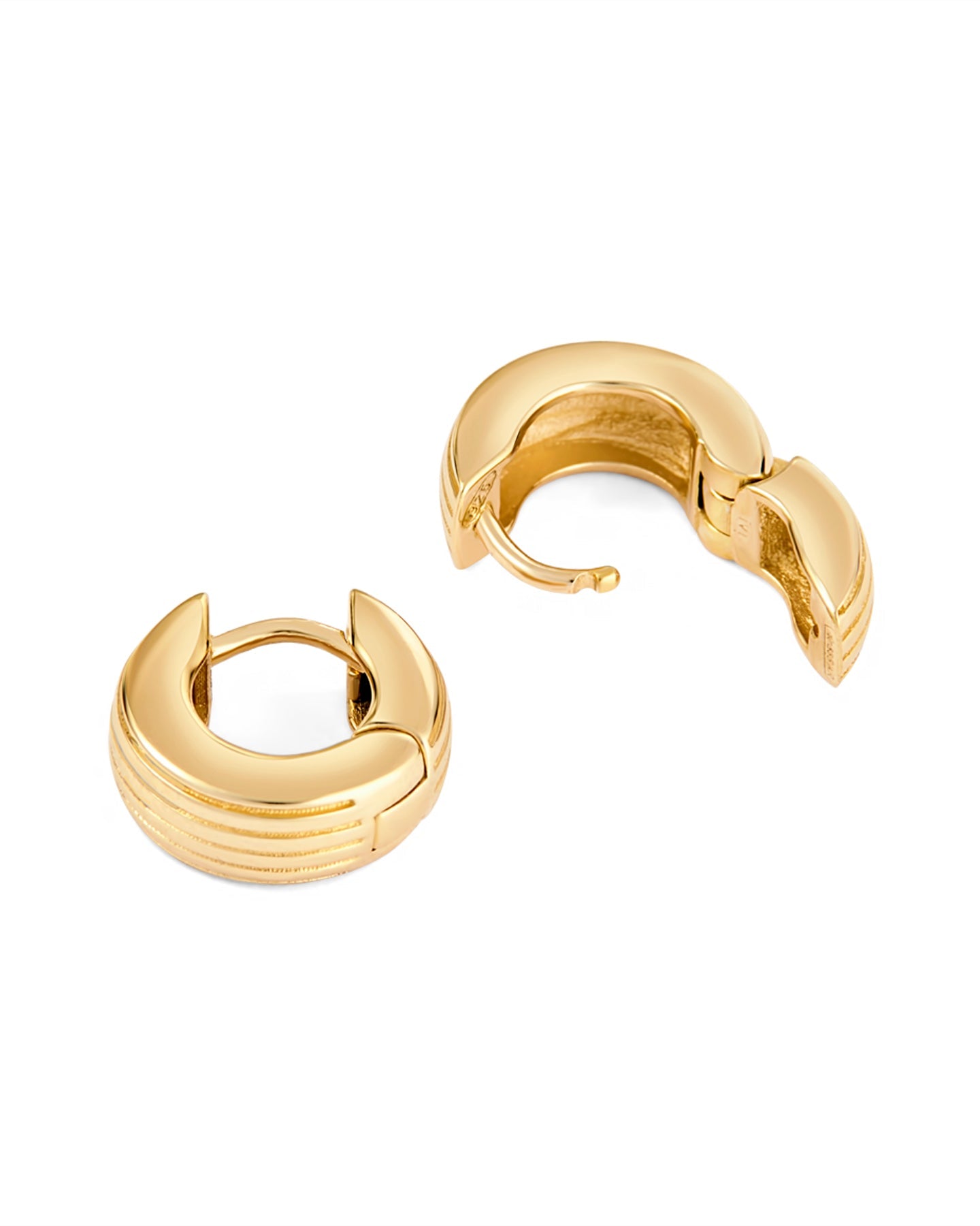 A pair of gold-plated round huggies earrings with a slim curved silhouette and engraved detailing on a white background.