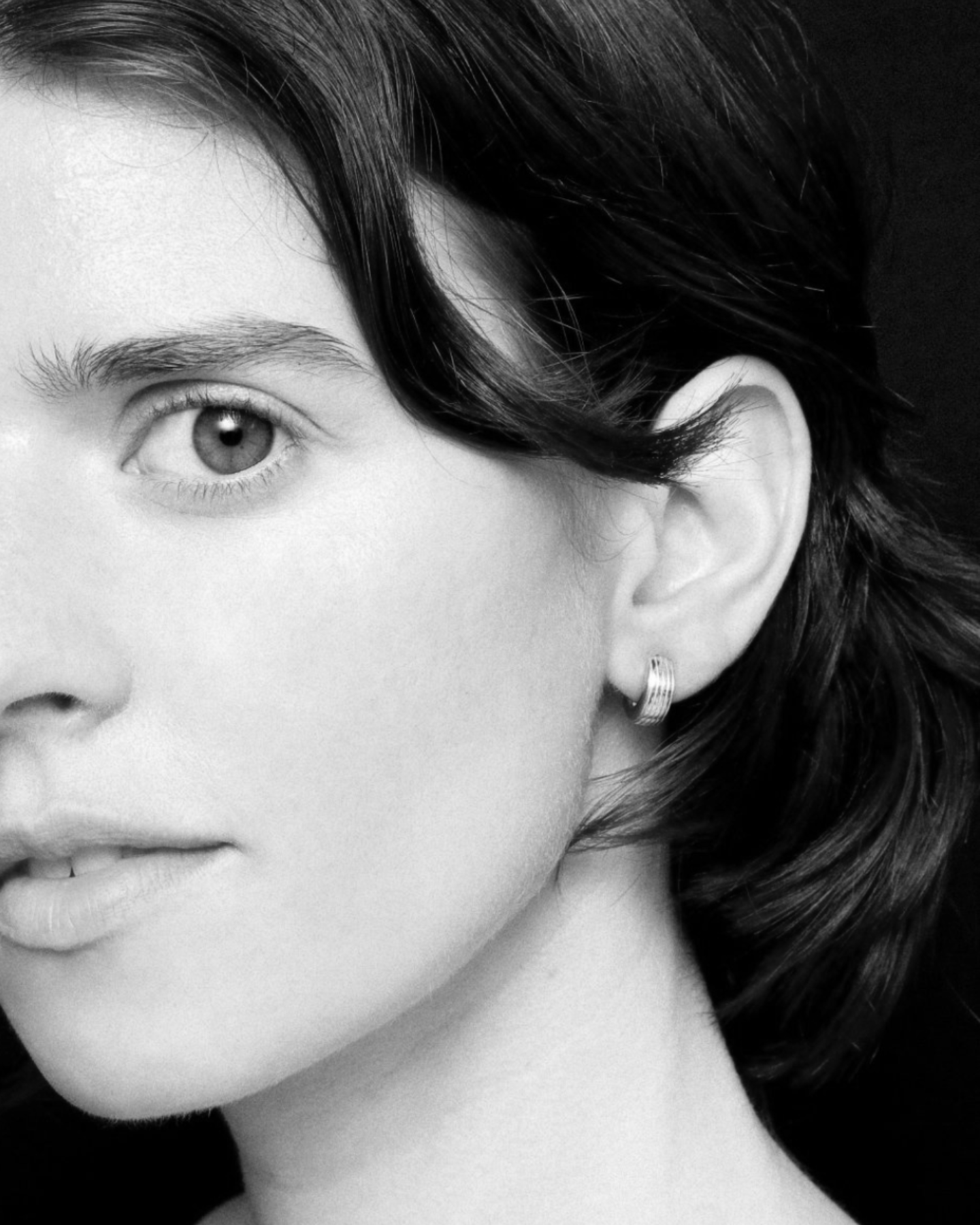 Close-up of a person wearing earrings with a black background