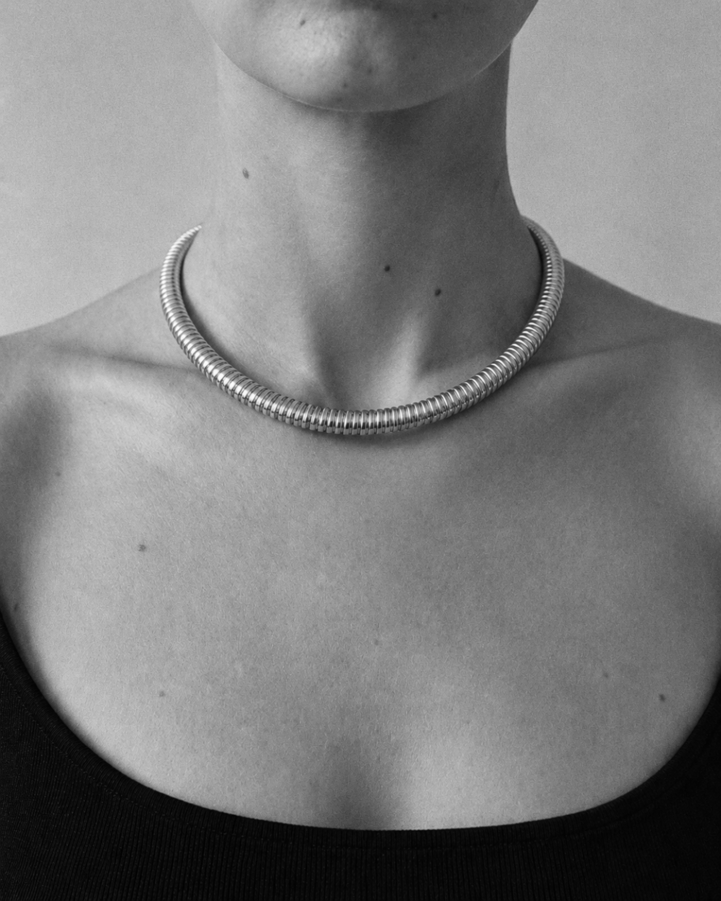Gold-plated tubogas necklace with a flexible ribbed design and concealed clasp worn by a model. 