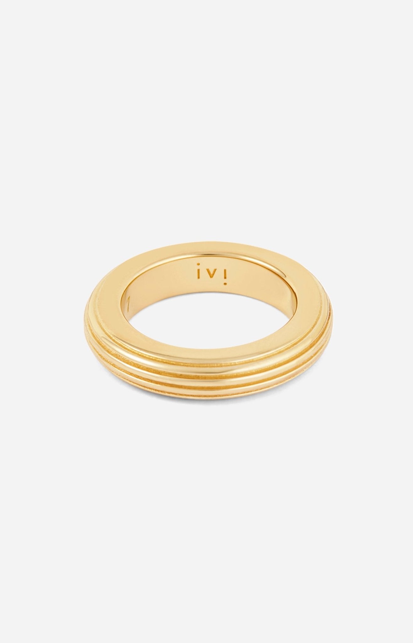A gold-plated, round-shaped ring with linear engravings on a white background. 