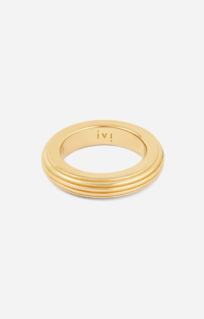 A gold-plated, round-shaped ring with linear engravings on a white background. 