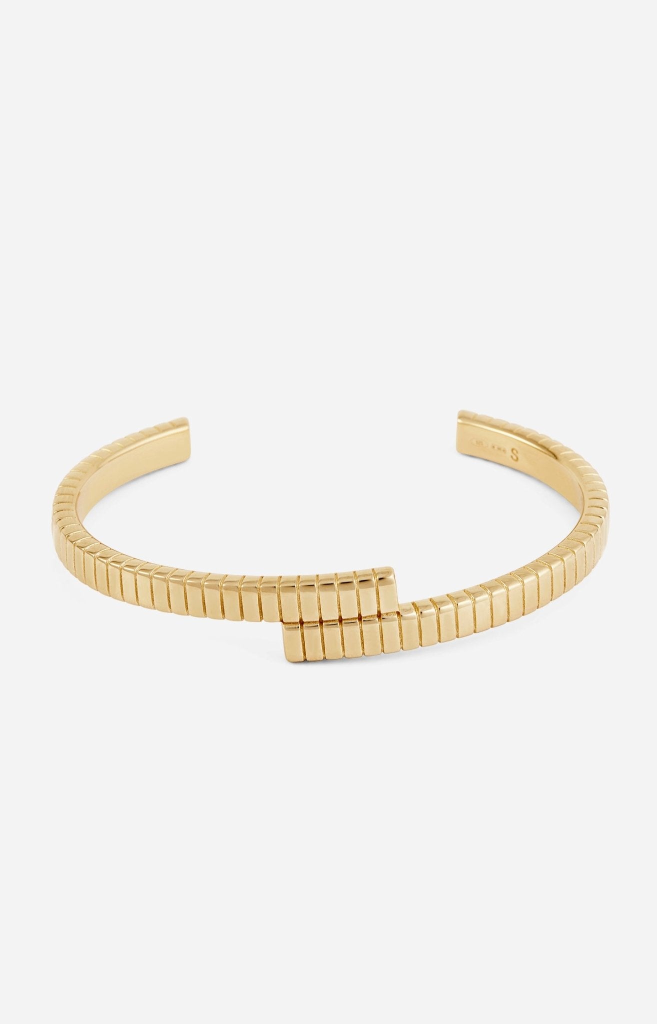A gold-plated cuff bracelet with a twisted design and linear engravings on a white background.