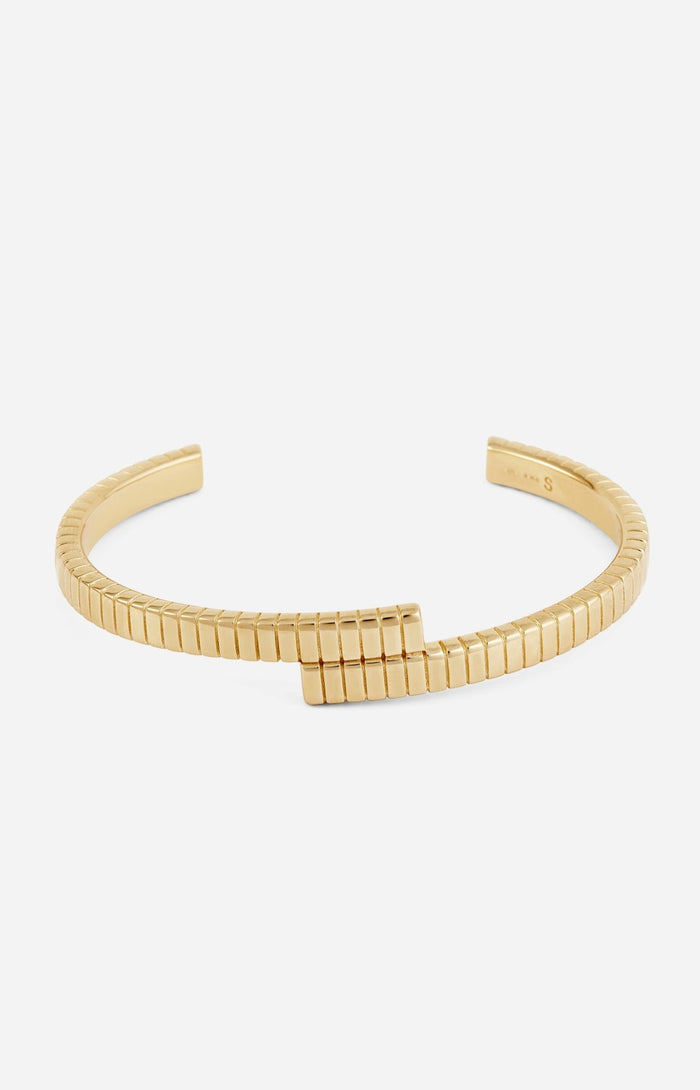 A gold-plated cuff bracelet with a twisted design and linear engravings on a white background.