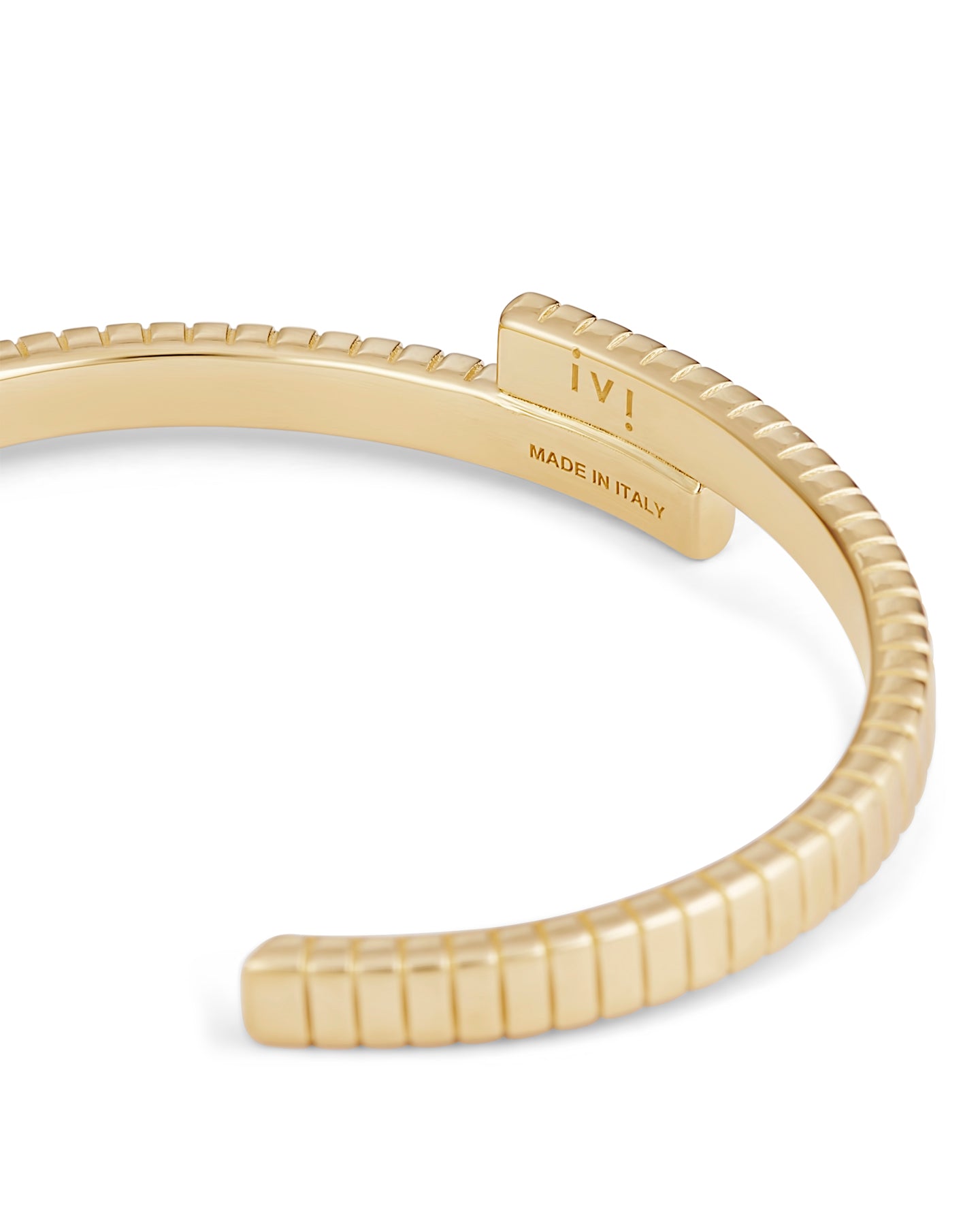 A gold-plated cuff bracelet with a twisted design and linear engravings on a white background.