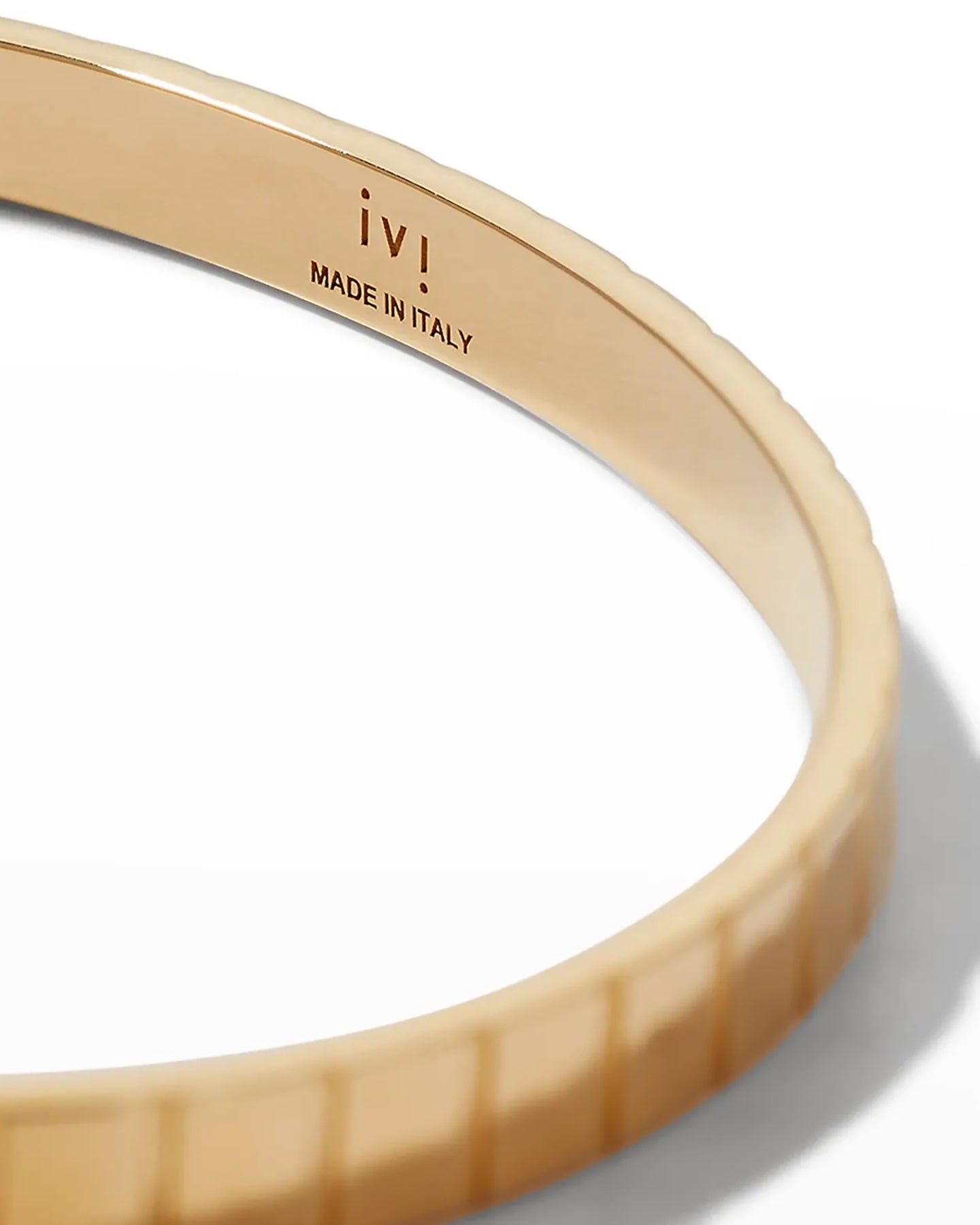 A close up of a gold-plated single slot cuff bracelet with a grooved profile on a white background.