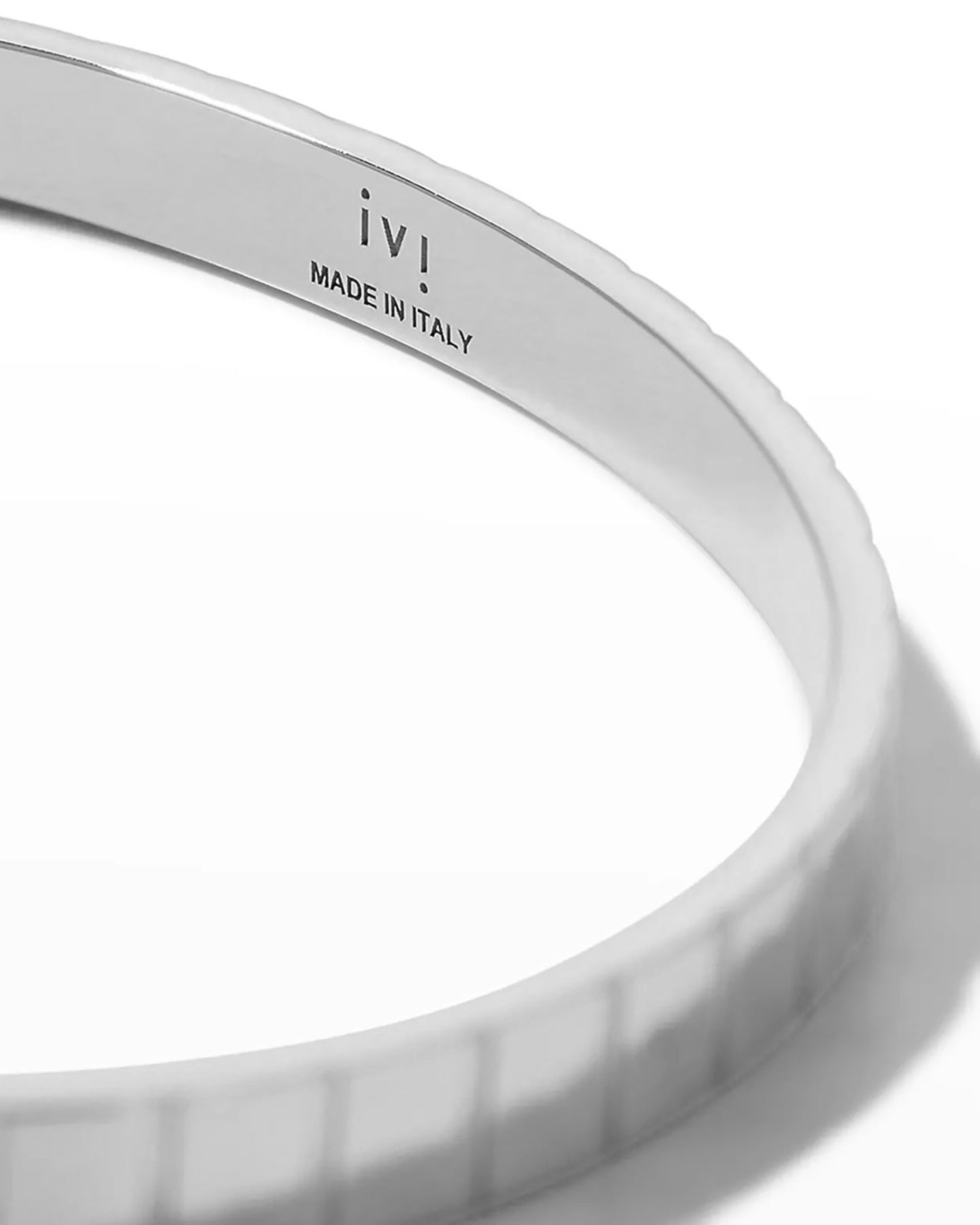 A close up of a rhodium-plated single slot cuff bracelet with a grooved profile on a white background.